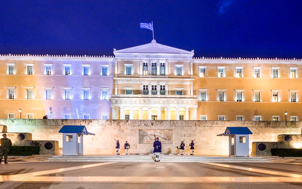 Greek Parliament building at Syntagma Square, Athens, with ceremonial guards.