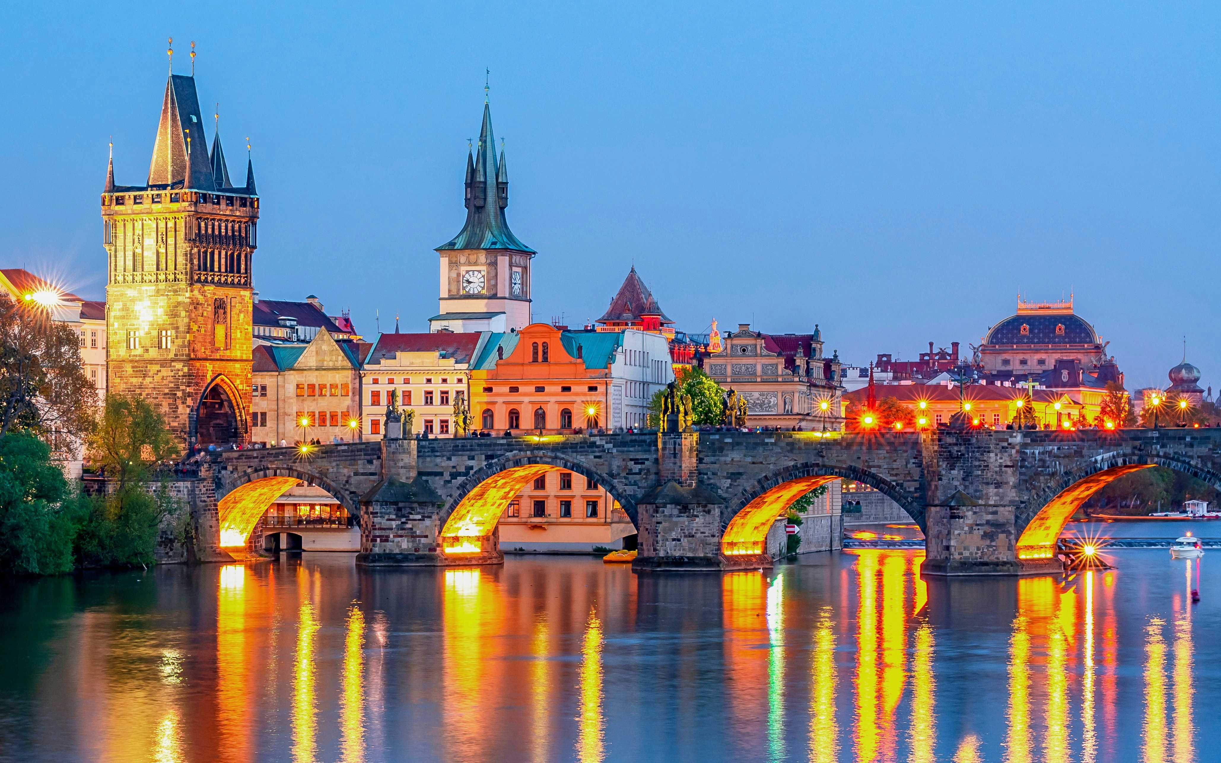 Charles Bridge illuminated over Vltava River with Prague's medieval architecture at night, Czech Republic.