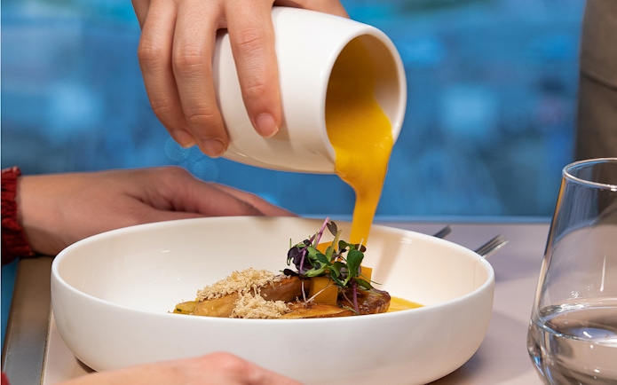 Pouring sauce over a gourmet dish at Madame Brasserie, Paris.