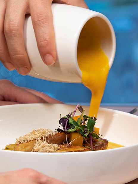 Pouring sauce over a gourmet dish at Madame Brasserie, Paris.