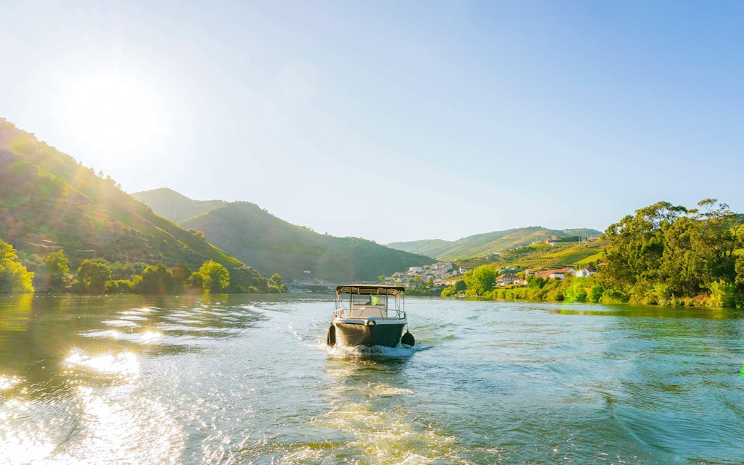 Boat cruising on Douro River in Douro Valley at sunset.