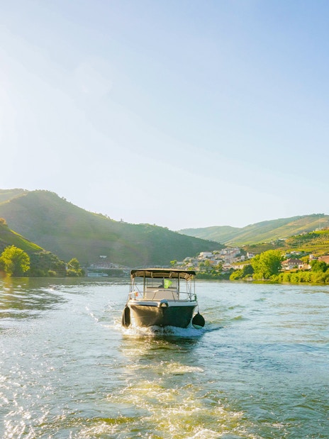 Boat cruising on Douro River in Douro Valley at sunset.