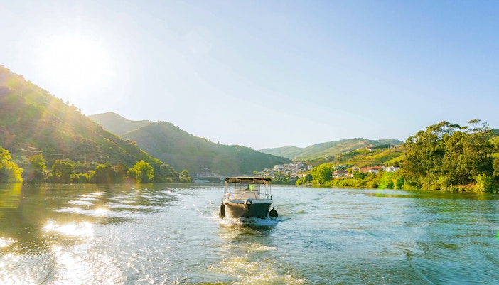 Boat cruising on Douro River in Douro Valley at sunset.