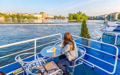 Person enjoying Vltava River view from a cruise deck in Prague.