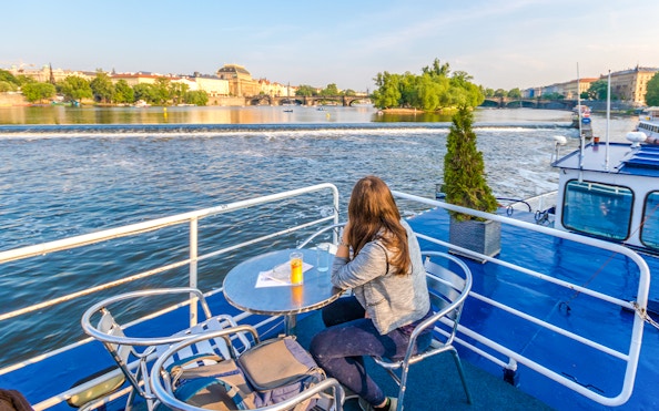 Person enjoying Vltava River view from a cruise deck in Prague.