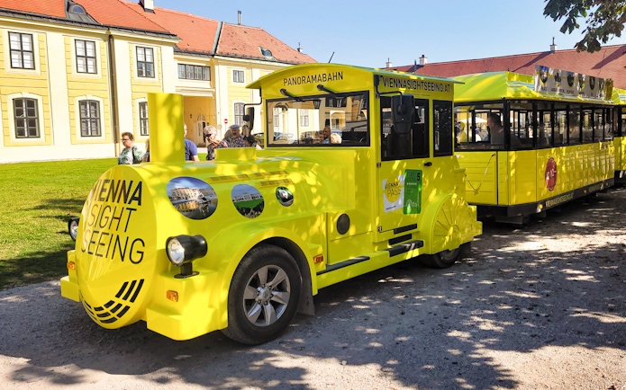Panorama train at Schönbrunn Palace, Vienna, with tourists boarding.