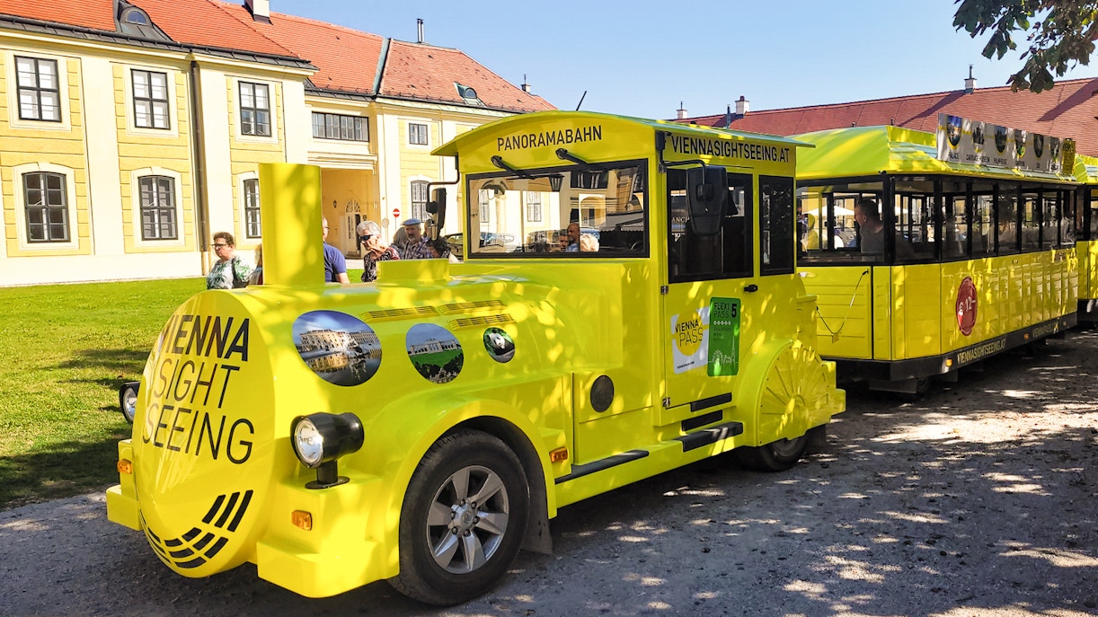 Panorama train at Schönbrunn Palace, Vienna, with tourists boarding.