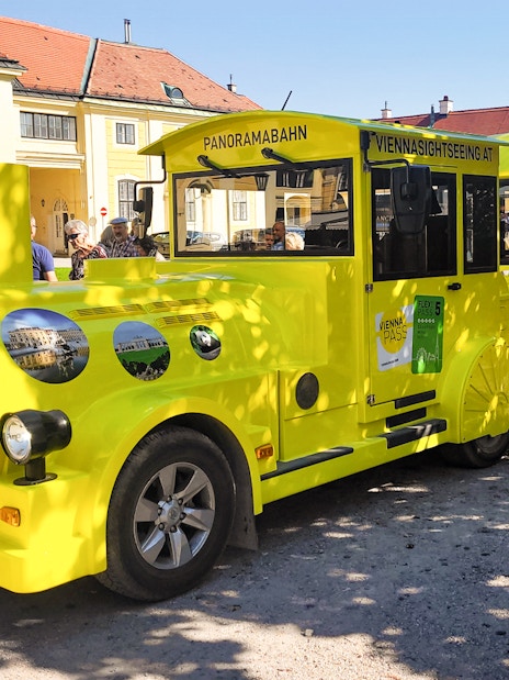 Panorama train at Schönbrunn Palace, Vienna, with tourists boarding.