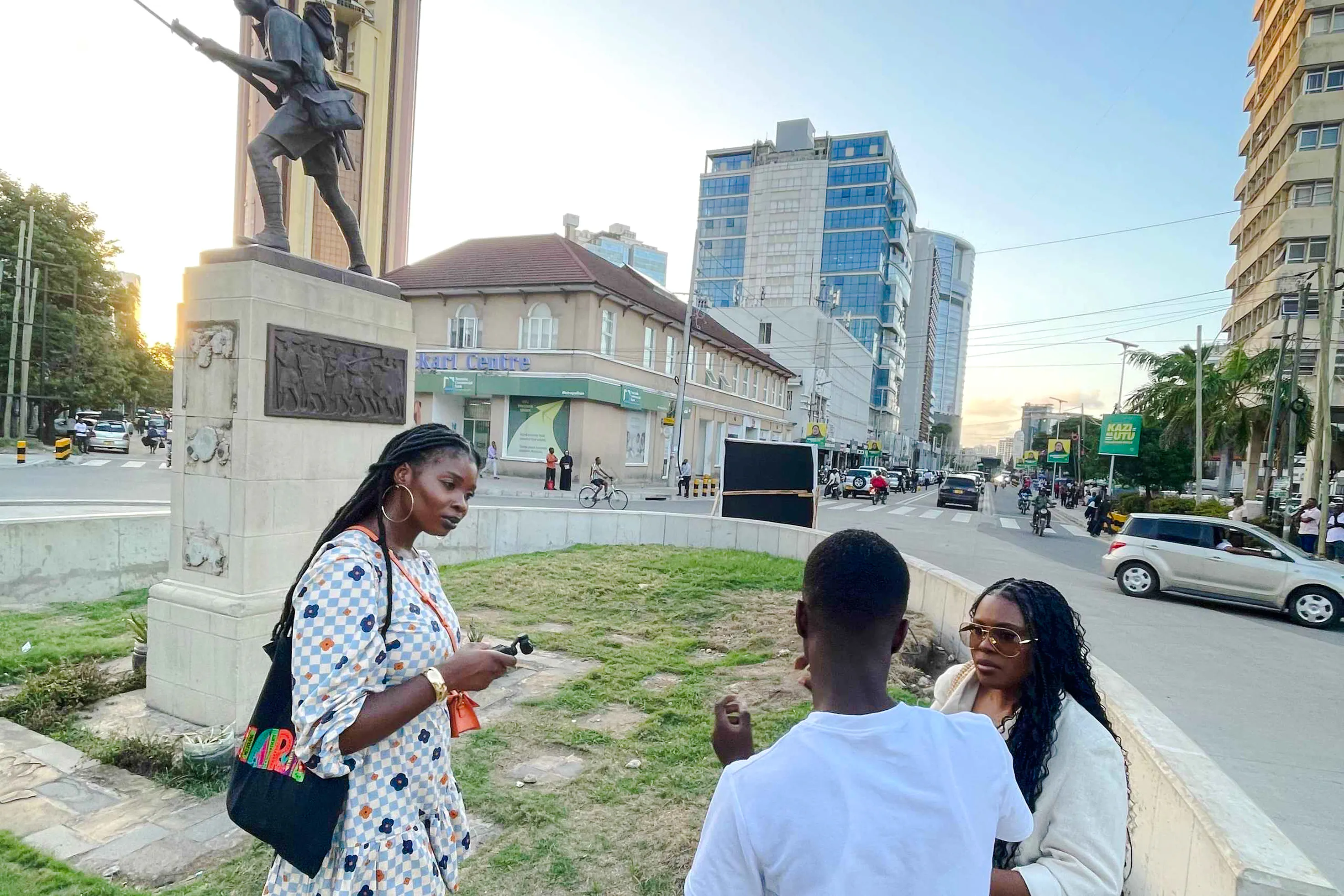 Tourists with a guide near a statue in a bustling street, Zanzibar.