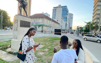 Tourists with a guide near a statue in a bustling street, Zanzibar.