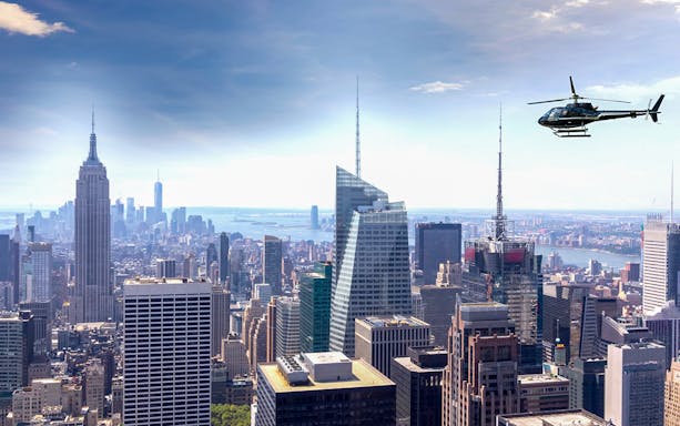 Helicopter flying over Manhattan skyline with Empire State Building.