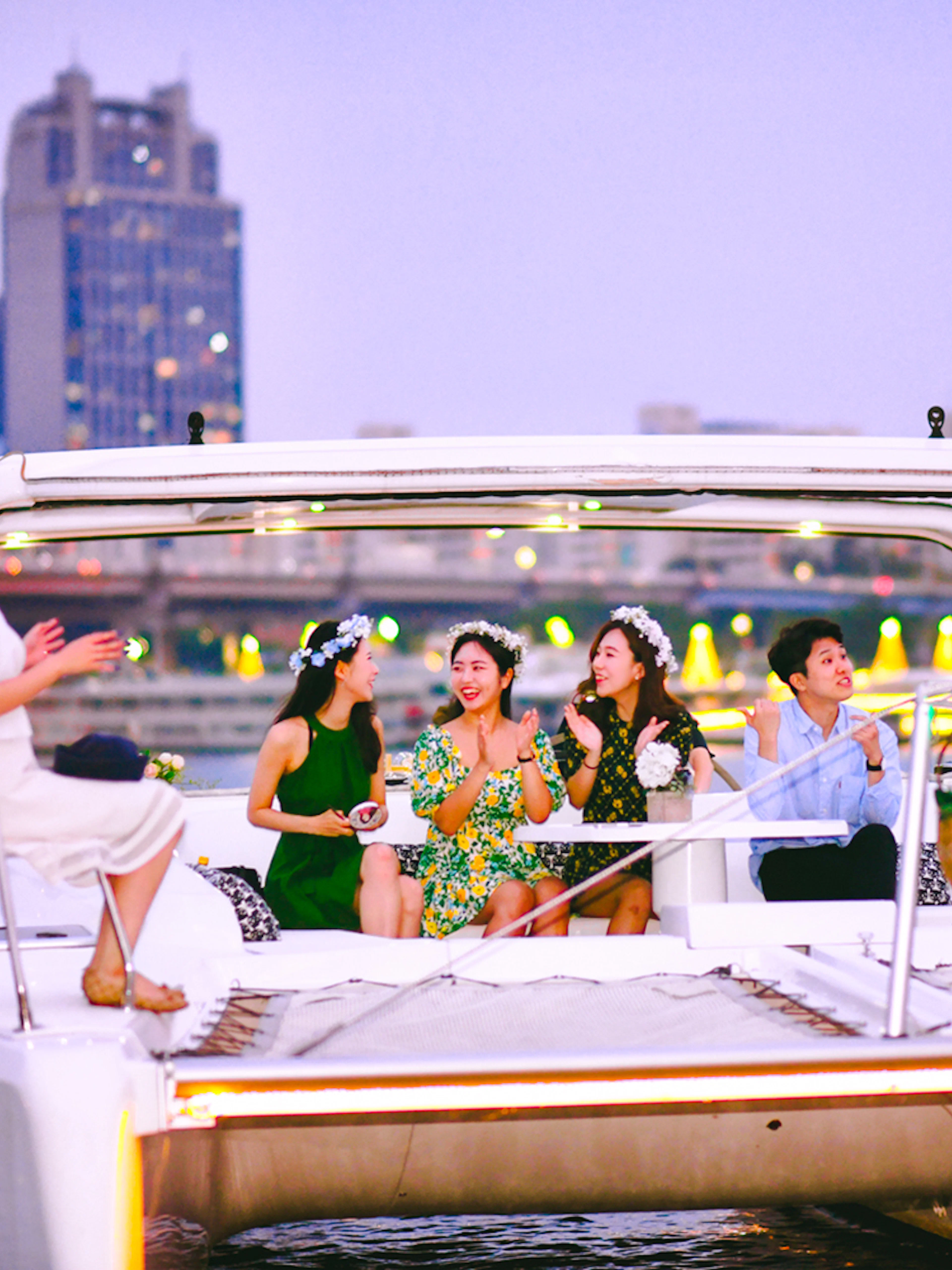 People enjoying a yacht cruise on the Han River in Seoul with city skyline in the background.