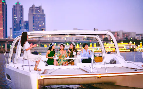 People enjoying a yacht cruise on the Han River in Seoul with city skyline in the background.