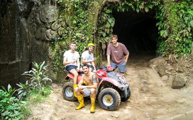 Group on ATV in front of jungle cave during Bali quad bike tour.