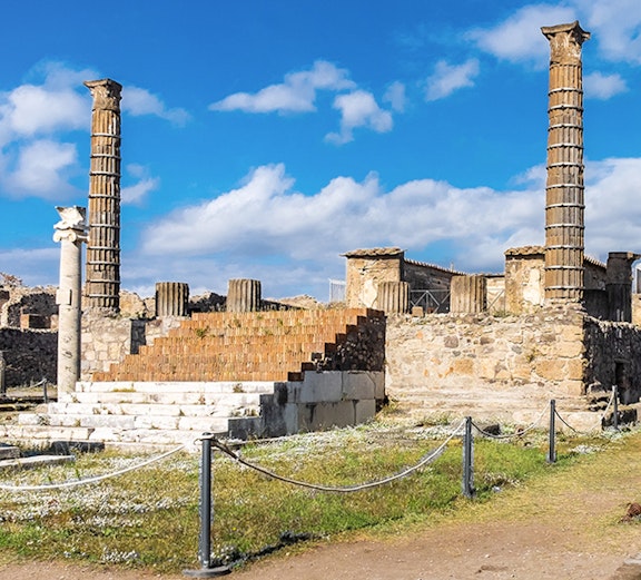 Ancient ruins with columns in Pompeii, Italy, viewed on a Naples to Pompeii tour.