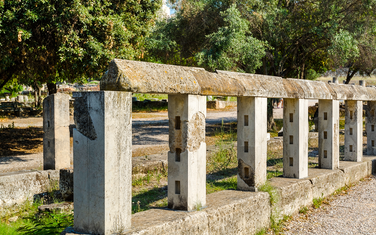 Monument of the Eponymous Heroes in Ancient Agora, Athens, with stone structure and trees.