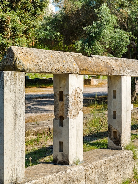 Monument of the Eponymous Heroes in Ancient Agora, Athens, with stone structure and trees.