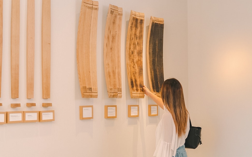 Person examining wine barrel staves display at a wine experience tour.