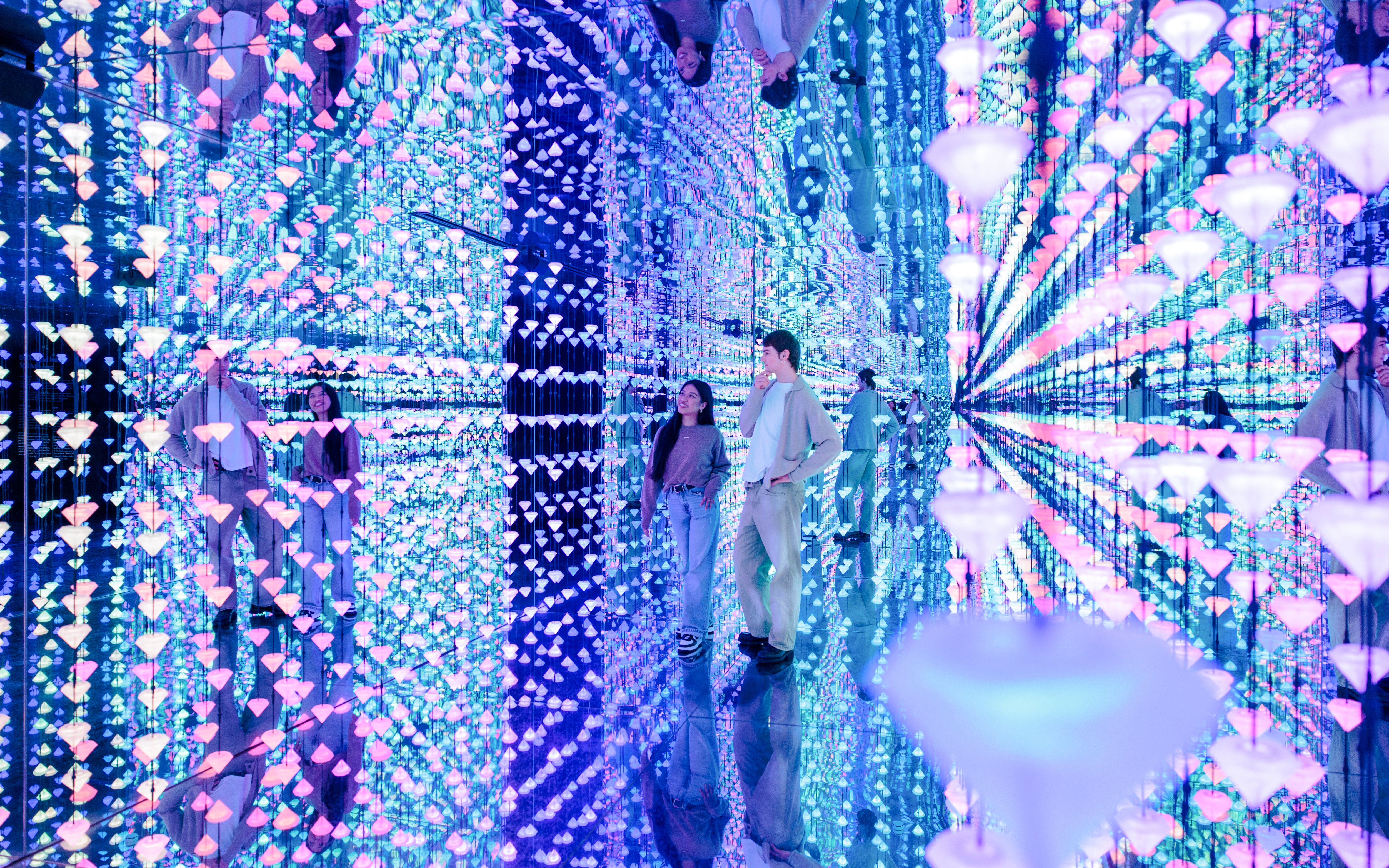 Visitors exploring a mirrored room with colorful lights at Moco Museum Barcelona.