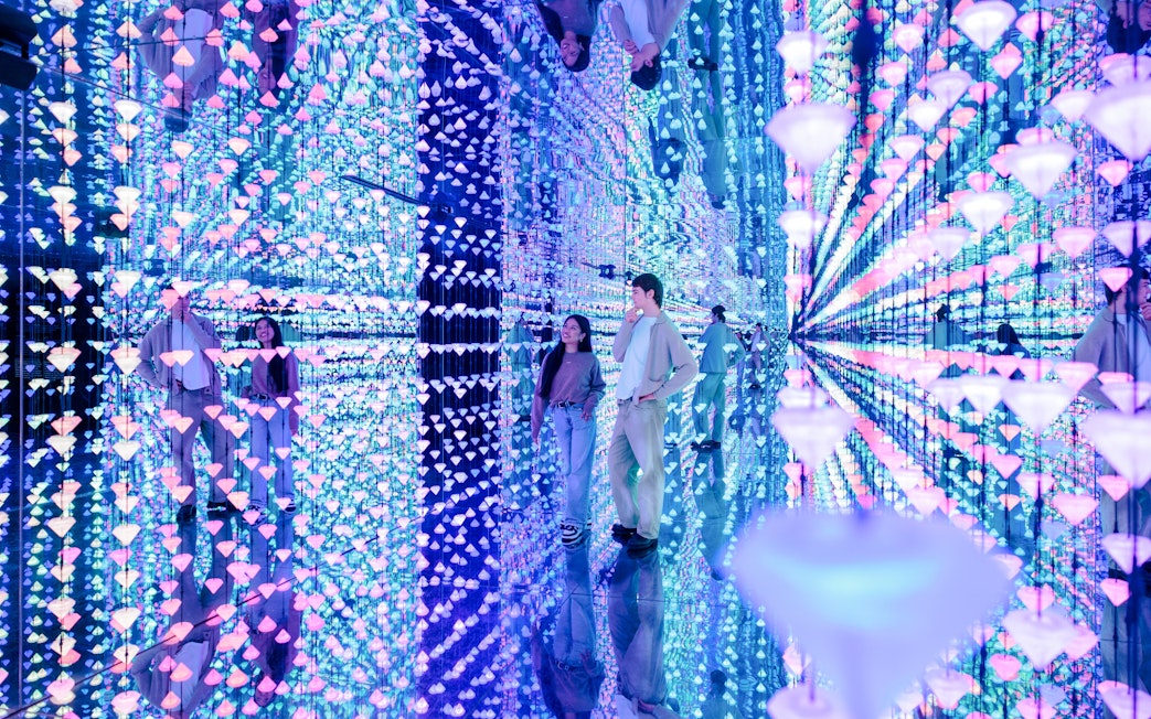 Visitors exploring a mirrored room with colorful lights at Moco Museum Barcelona.