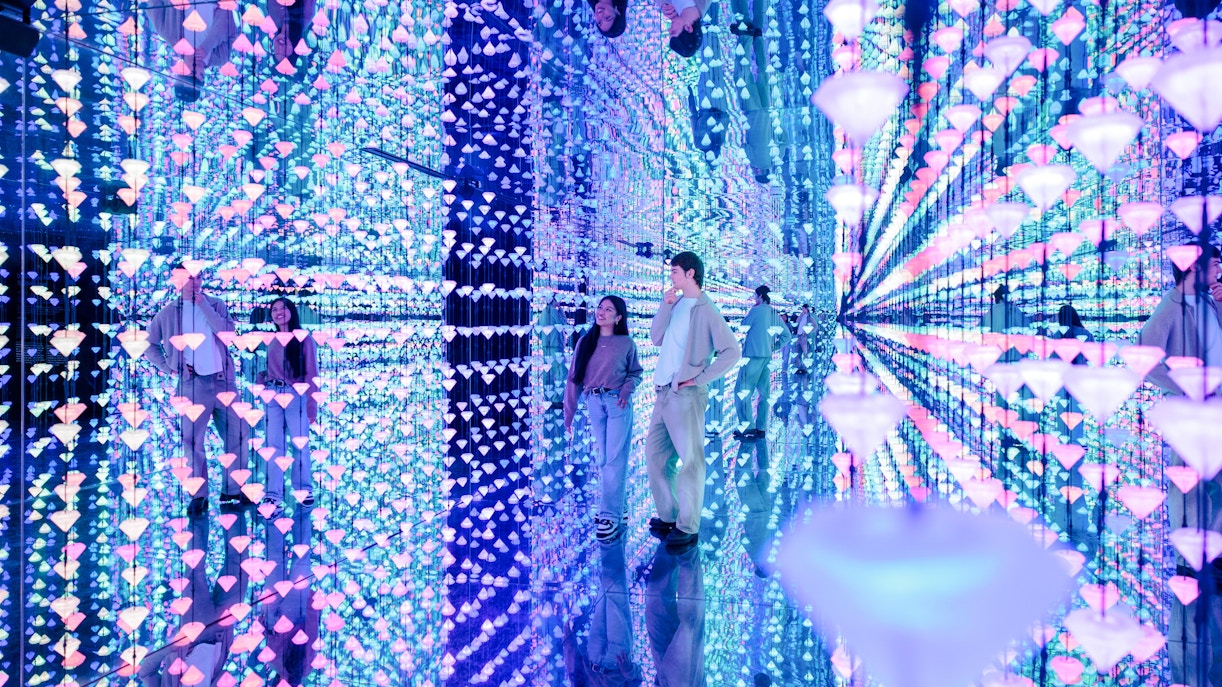 Visitors exploring a mirrored room with colorful lights at Moco Museum Barcelona.