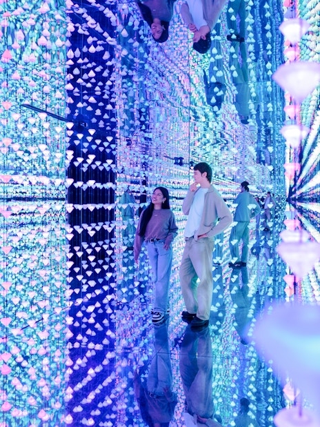 Visitors exploring a mirrored room with colorful lights at Moco Museum Barcelona.