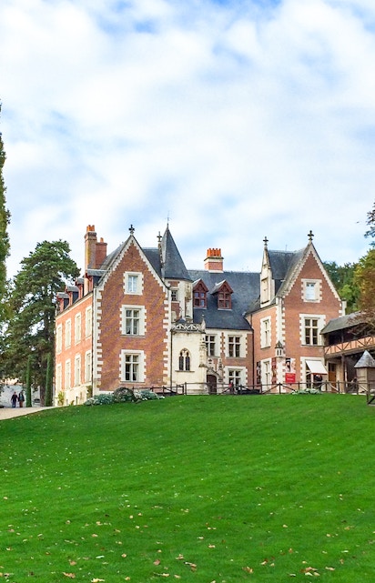 Château du Clos Lucé in Loire Valley with green lawn and trees.
