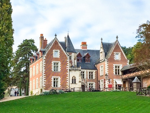 Château du Clos Lucé in Loire Valley with green lawn and trees.