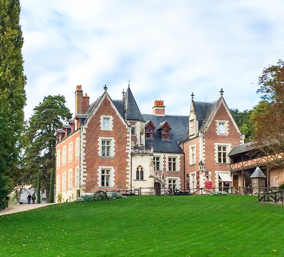 Château du Clos Lucé in Loire Valley with green lawn and trees.