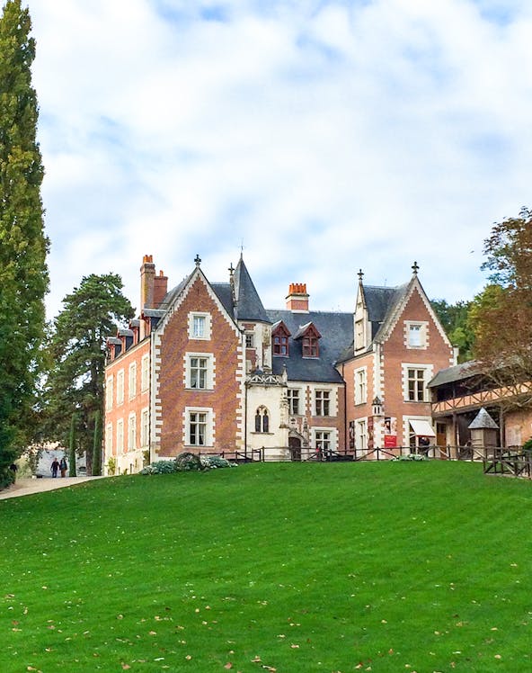 Château du Clos Lucé in Loire Valley with green lawn and trees.