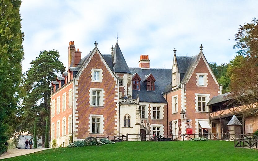 Château du Clos Lucé in Loire Valley with green lawn and trees.