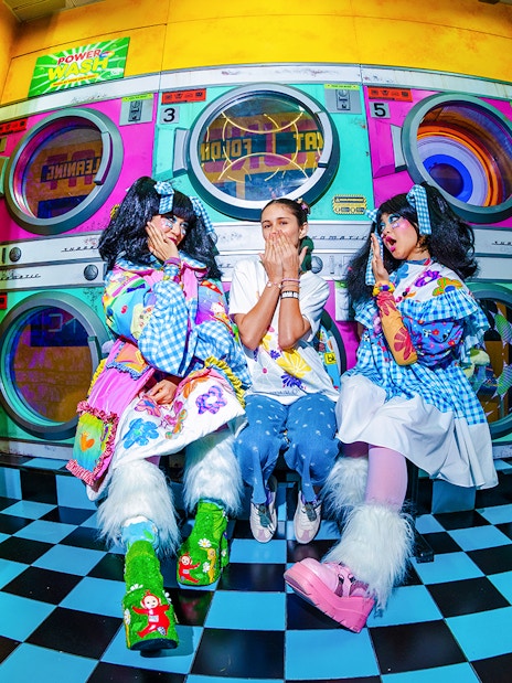 Tourists interacting with performers at House of Hype in colorful laundromat setting.