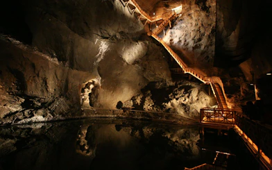 Wieliczka Salt Mine underground chamber with illuminated wooden stairs and rock formations.