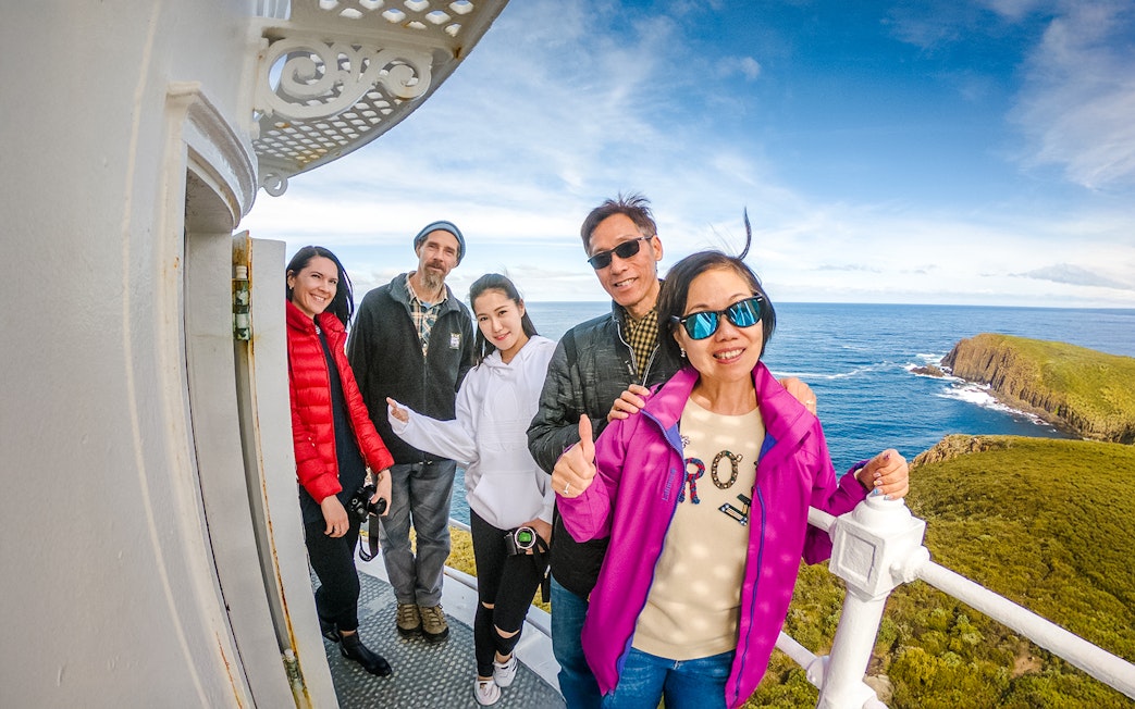 Family on Bruny Island lighthouse balcony with ocean view.