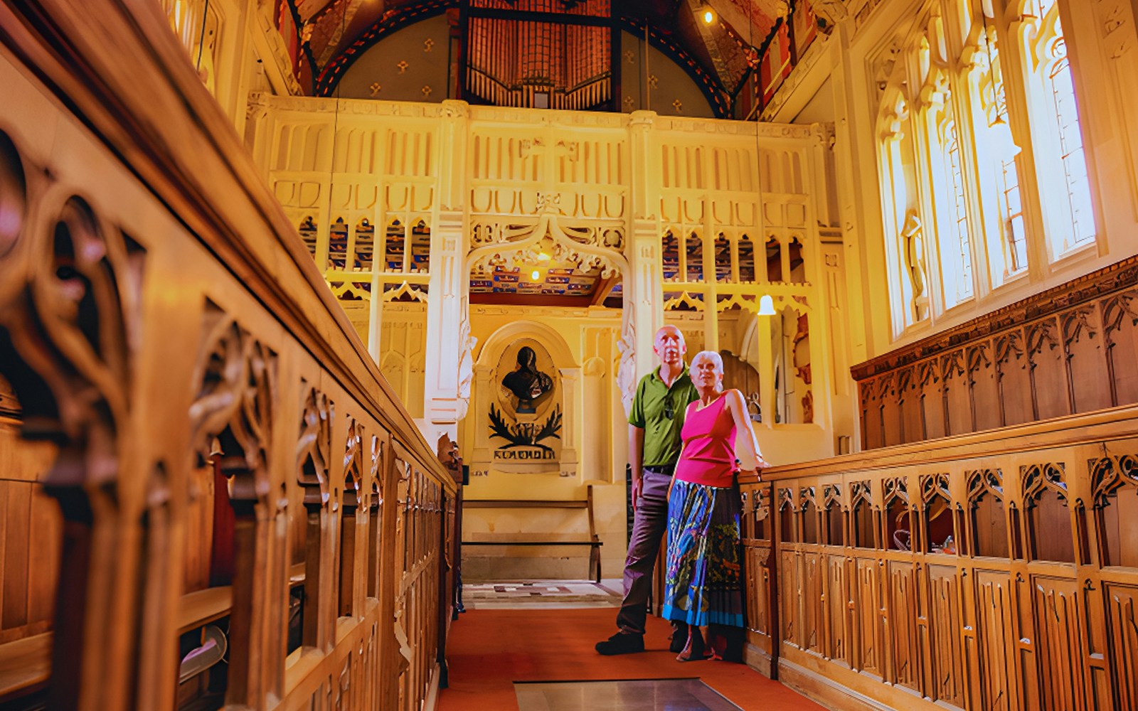 Visitors inside St Nicholas' Chapel, admiring intricate wooden carvings and stained glass windows.