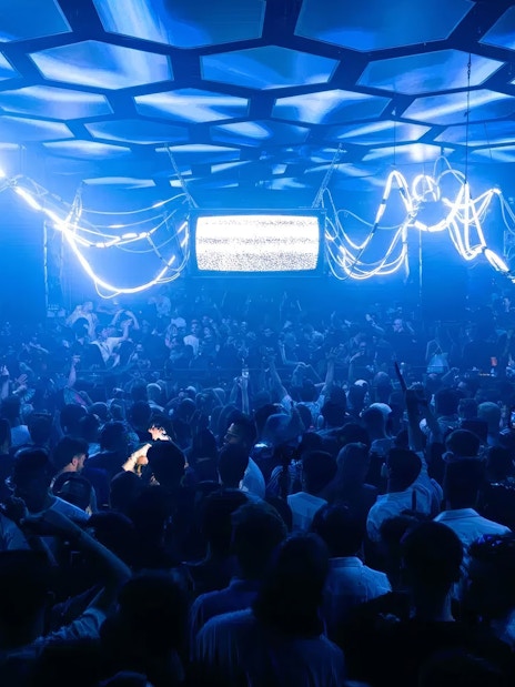 DJ performing at Music On event, Pacha Ibiza nightclub, with vibrant crowd and neon lights.