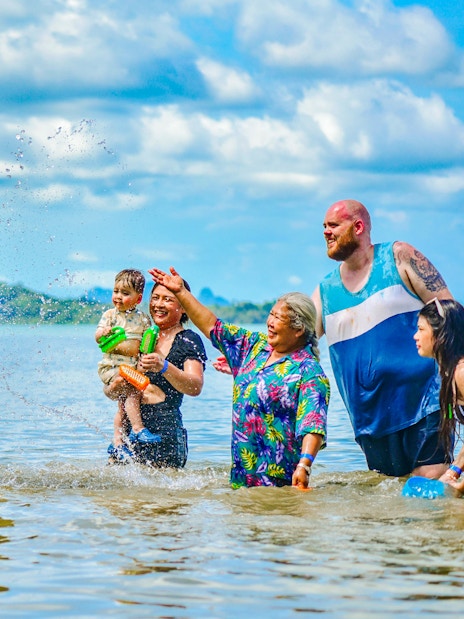 People interacting with an elephant at Lily Elephant Camp, Phuket beach.