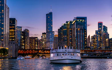 Chicago River cruise boat at night with city skyline in the background.