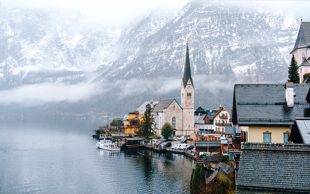 Hallstatt Church by a lake in winter, surrounded by snow-covered mountains, Austria.