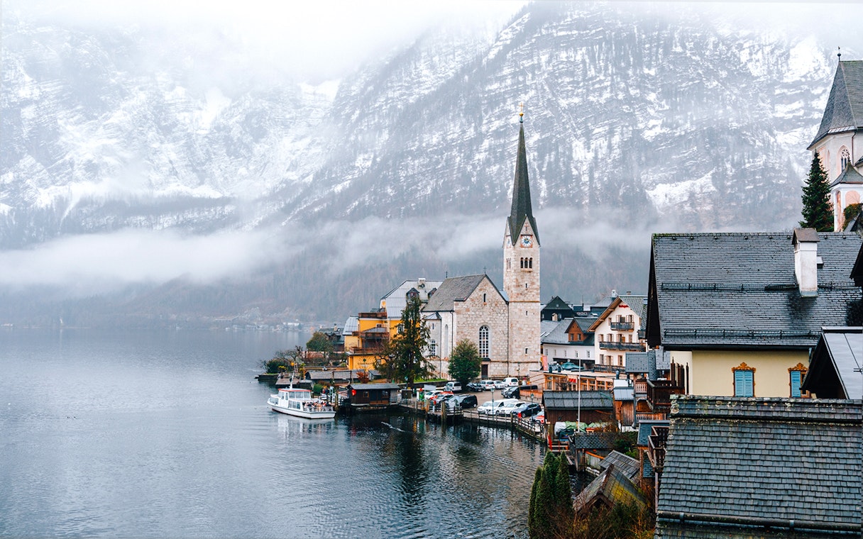 Hallstatt Church by a lake in winter, surrounded by snow-covered mountains, Austria.