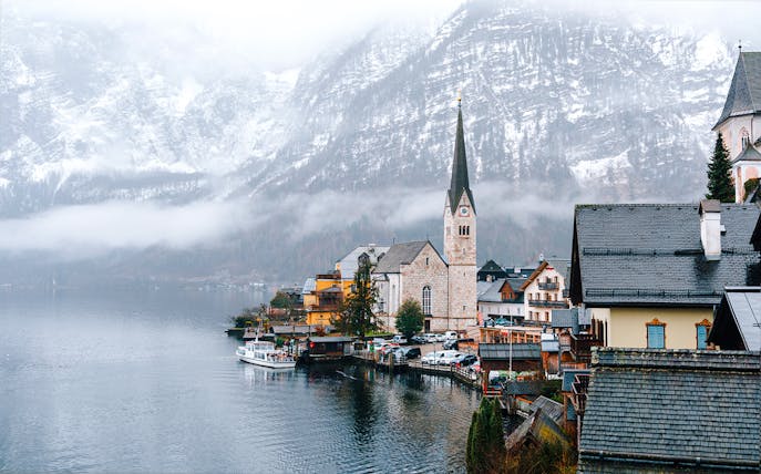 Hallstatt Church by a lake in winter, surrounded by snow-covered mountains, Austria.