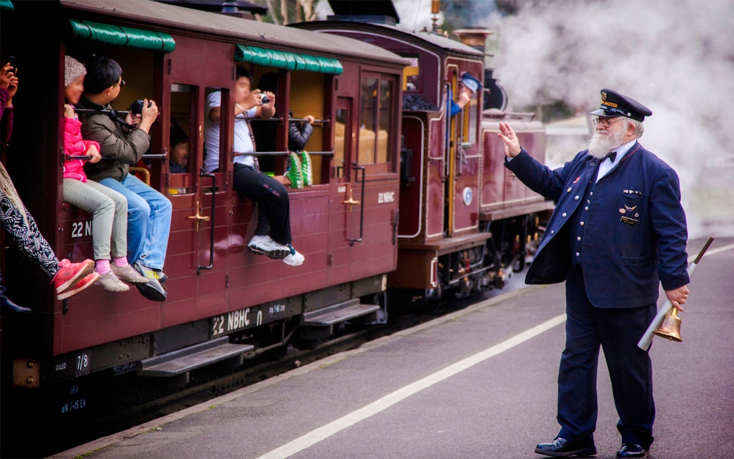 Conductor waves as Puffing Billy steam train departs on a half-day tour from Melbourne.