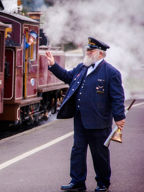 Conductor waves as Puffing Billy steam train departs on a half-day tour from Melbourne.