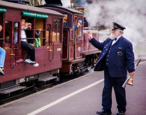 Conductor waves as Puffing Billy steam train departs on a half-day tour from Melbourne.