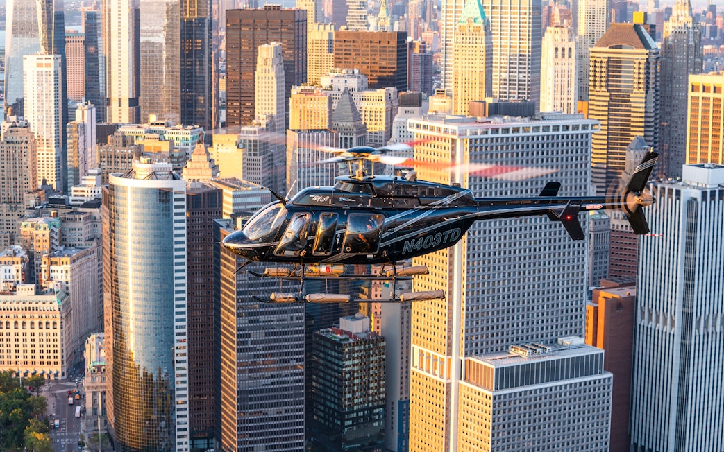 Helicopter flying over New York City skyline with skyscrapers in view.