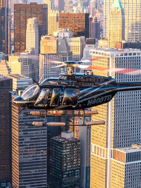 Helicopter flying over New York City skyline with skyscrapers in view.