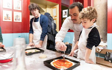 Participants in a Rome kitchen making pizza during a cooking class.