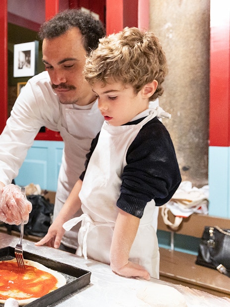 Participants in a Rome kitchen making pizza during a cooking class.