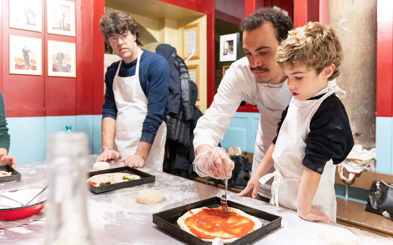 Participants in a Rome kitchen making pizza during a cooking class.
