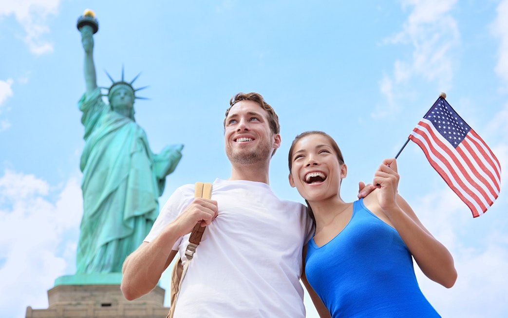 Tourists with American flag near Statue of Liberty, New York City.